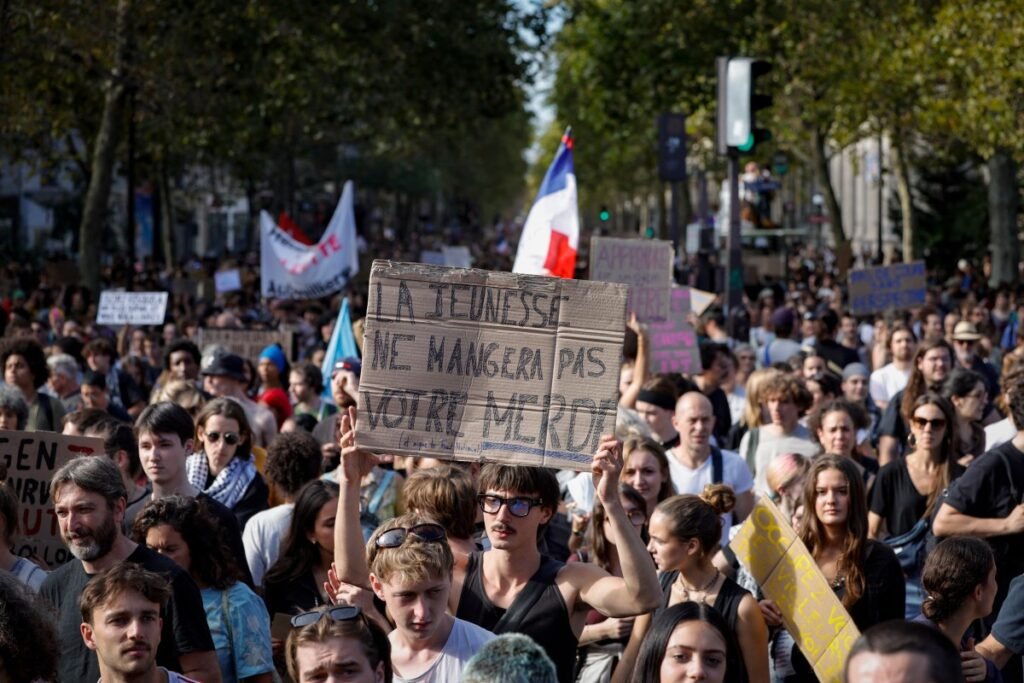 A person hold a placard reading in French "Youth won't eat your shit" during a demonstration part of a nationwide day of actions called by high-school students, joined by unions and teachers, who for days have been demanding better learning conditions in protests punctuated by violent confrontations in Paris on October 6, 2026. Students have blocked the entrances to hundreds of high schools for 15- to 17-year-olds since late September, complaining of missing teachers, overloaded timetables, dilapidated classrooms and buildings that cannot cope with rising temperatures. (Photo by GEOFFROY VAN DER HASSELT / AFP)
