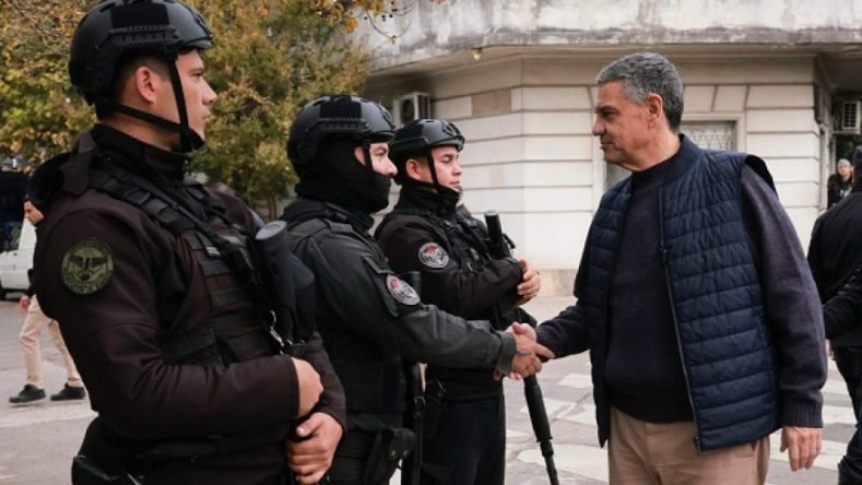 Esta imagen muestra al jefe de Gobierno de la Ciudad de Buenos Aires, Jorge Macri, saludando a efectivos de la Policía de la Ciudad durante una supervisión de los controles de seguridad en los accesos viales.
