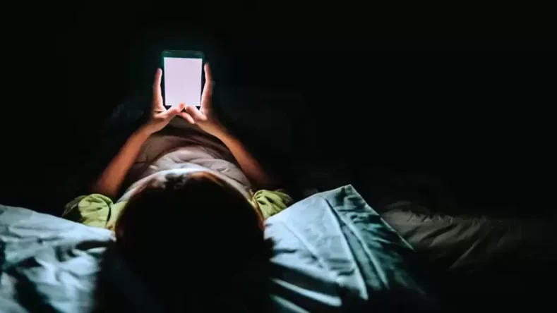 Imagen ilustrativa vista de arriba de una persona acostada usando el celular
