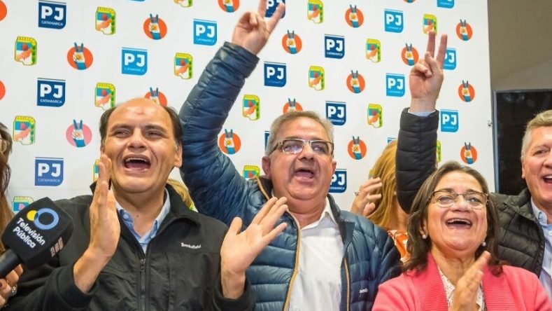 La imagen muestra al gobernador de Catamarca, Raúl Jalil, junto al intendente de la capital Gustavo Saadi y la senadora nacional Lucía Corpacci. El grupo celebra los resultados electorales del oficialismo provincial (Partido Justicialista / Unión por la Patria) en la sede partidaria.