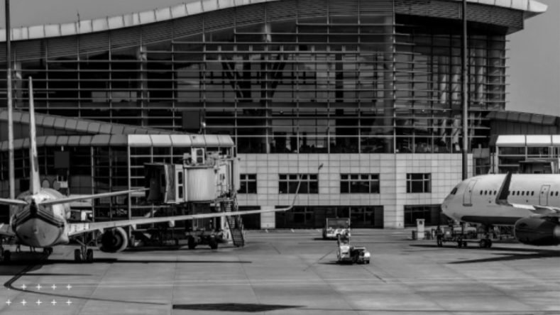 La imagen muestra una terminal aeroportuaria moderna con aviones estacionados en la plataforma, evidenciando actividad aérea.