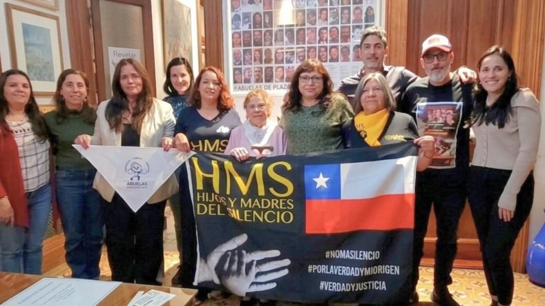 La imagen muestra a integrantes de la fundación chilena Hijos y Madres del Silencio (HMS) junto a autoridades y representantes de Abuelas de Plaza de Mayo en Buenos Aires, durante la firma de un convenio de cooperación para la búsqueda de bebés y niños apropiados ilegalmente durante la dictadura en Chile.