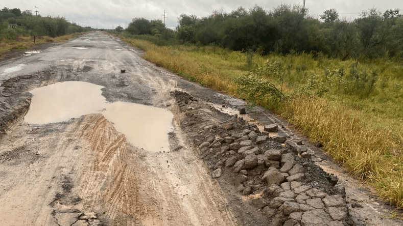 La imagen muestra una ruta rural gravemente deteriorada con baches profundos, acumulación de agua y banquinas destruidas en el norte argentino. [1] (https://www.clarin.com/rural/necesidad-transversal-entidad-realizo-recorrida-provincias-norte-alerto-falta-infraestructura-mal-estado-rutas_0_HpinUuexZJ.html), [2] (https://www.transporteyenergia.com.ar/Noticias/Noticias-202606/de-gira-por-el-norte-cra-reclamo-por-la-infraestructura-sin-rutas-y-ca.html)