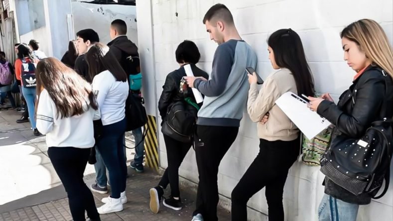 Esta imagen muestra a un grupo de personas jóvenes haciendo fila en el exterior de un edificio, lo que resalta el difícil panorama del empleo juvenil en Argentina, donde la tasa de desempleo joven duplica o triplica a la de los adultos.