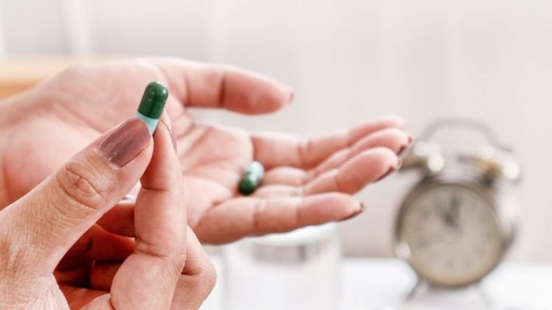 Imagen de mano tomando antibiótico en pastilla