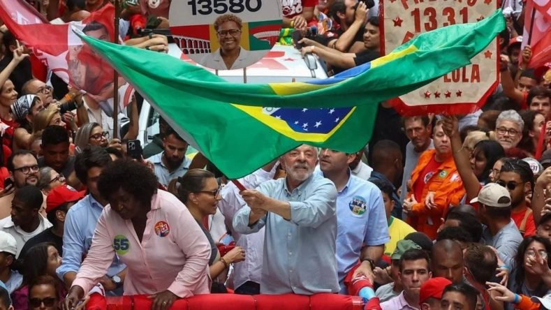 La imagen muestra al presidente de Brasil, Luiz Inácio Lula da Silva, participando en un mitin o caravana de campaña política rodeado de partidarios, según informan agencias internacionales de noticias.
