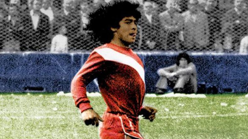 La imagen muestra a un joven Diego Armando Maradona vistiendo la clásica camiseta roja con la banda blanca diagonal de Argentinos Juniors, durante sus primeros años en el club de La Paternal.