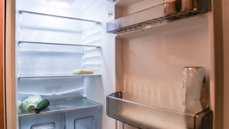 Almost empty  fridge with open door Surrey England