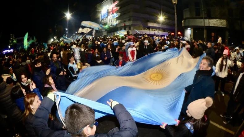 Esta imagen muestra una multitud celebrando un triunfo de la selección argentina de fútbol en las calles, posiblemente tras ganar la Copa América 2024 en La Plata.