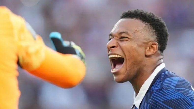 La imagen muestra al futbolista francés Kylian Mbappé celebrando efusivamente durante un partido de la selección de Francia en la Copa Mundial de la FIFA 2026.