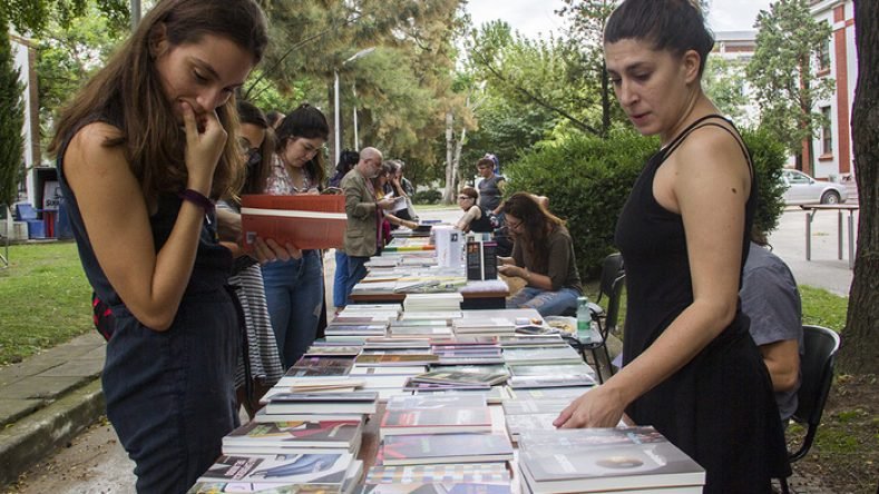 Imagen ilustrativa de jóvenes viendo libros para comprar.