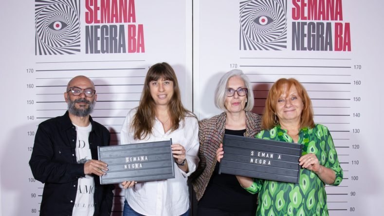 La imagen muestra a cuatro personas posando frente a un panel de medición de altura de la Semana Negra BA, el festival literario dedicado al género policial y negro en Buenos Aires.